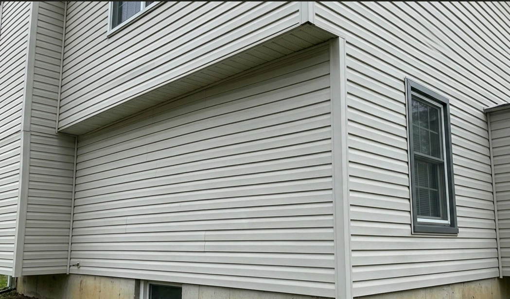 Clean beige vinyl siding after professional pressure washing removed all green algae stains.